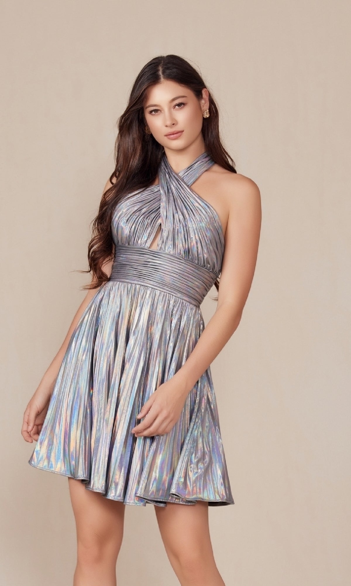 A woman models the Short Metallic Cut-Out Halter Hoco Dress K822, featuring a pleated skirt, while standing against a plain light background.